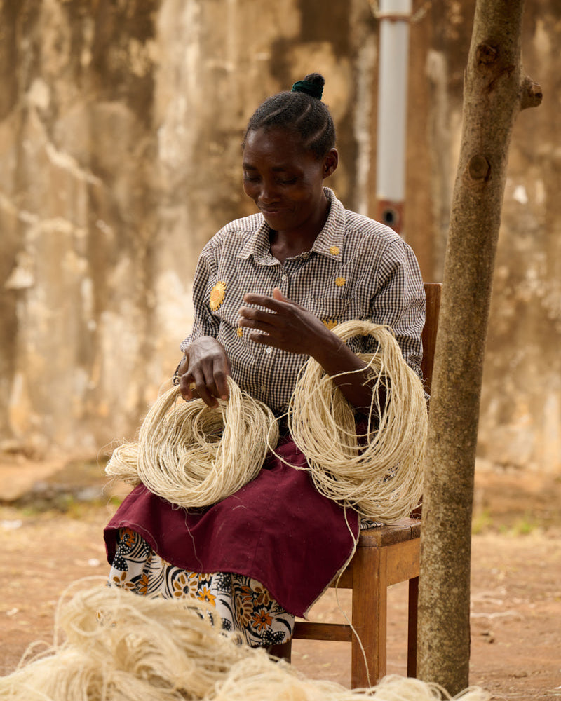 Woman sitting on a chair with bundles of sisal in an outdoor setting in Kenya