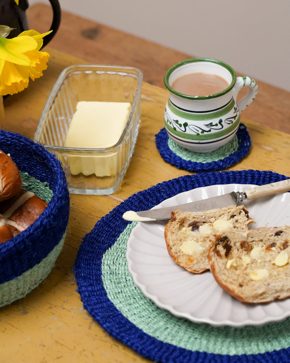 Breakfast scene with bread, butter, and a mug on a wooden table.