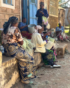 Group of women sitting and working with baskets in a rural setting