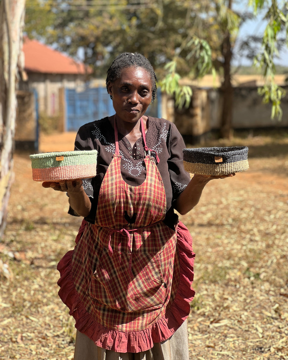 Woman holding two woven baskets outdoors with a rustic background