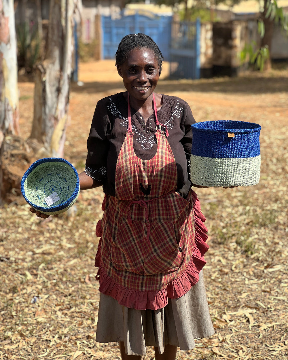 Female basket weaver holding blue and green baskets