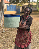 Woman holding a woven basket outdoors with a rural background